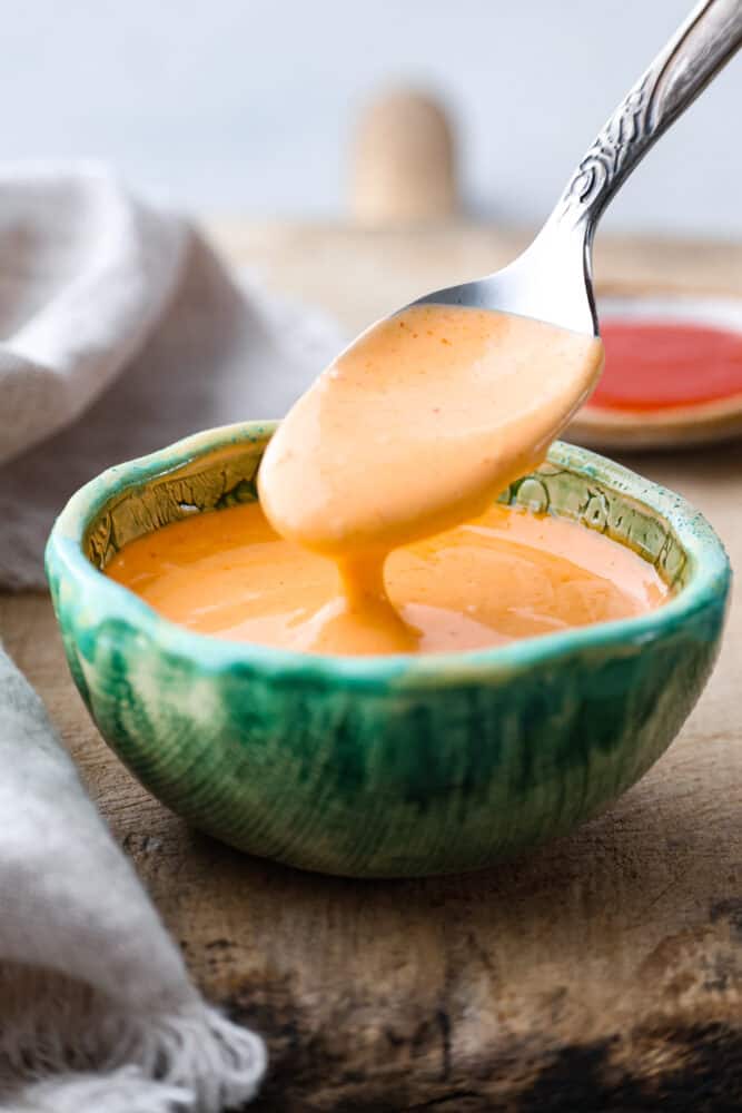 Sriracha mayo is the condiment youโre going to want to put on everything! Itโs creamy and savory, with spice that packs a punch! Hero image of a spoonful of sriracha mayo.
