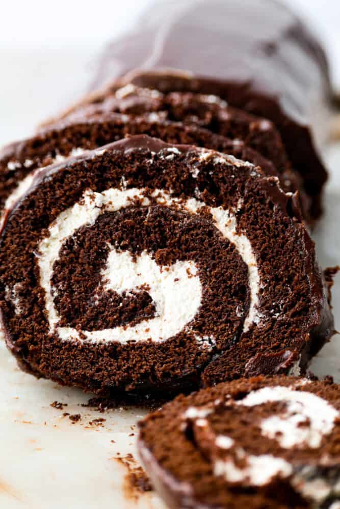 A classic and beautiful dessert, this Swiss Roll Cake is a rich chocolate sponge filled with pillowy whipped cream and covered in a chocolate ganache. This dessert is not only stunning, it's also incredibly tasty and every chocolate lover's dream! A close up on the Swiss roll cake.