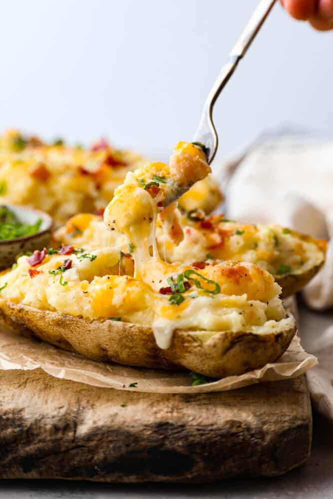 What's better than a regular baked potato? A twice baked potato, of course! They are the ultimate comfort food - creamy, savory, and packed with cheesy goodness. Whether you're cooking for one or for a crowd, these spuds are easy to make and impossible to resist. Taking a bite of a twice baked potato with a fork.