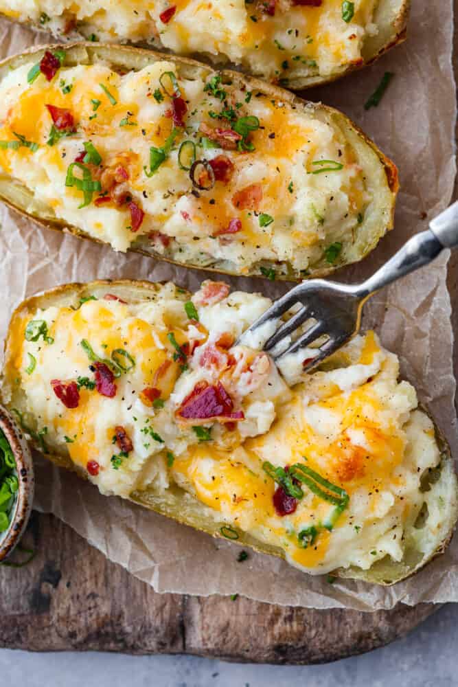 What's better than a regular baked potato? A twice baked potato, of course! They are the ultimate comfort food - creamy, savory, and packed with cheesy goodness. Whether you're cooking for one or for a crowd, these spuds are easy to make and impossible to resist. Top-down view of 2 potatoes.