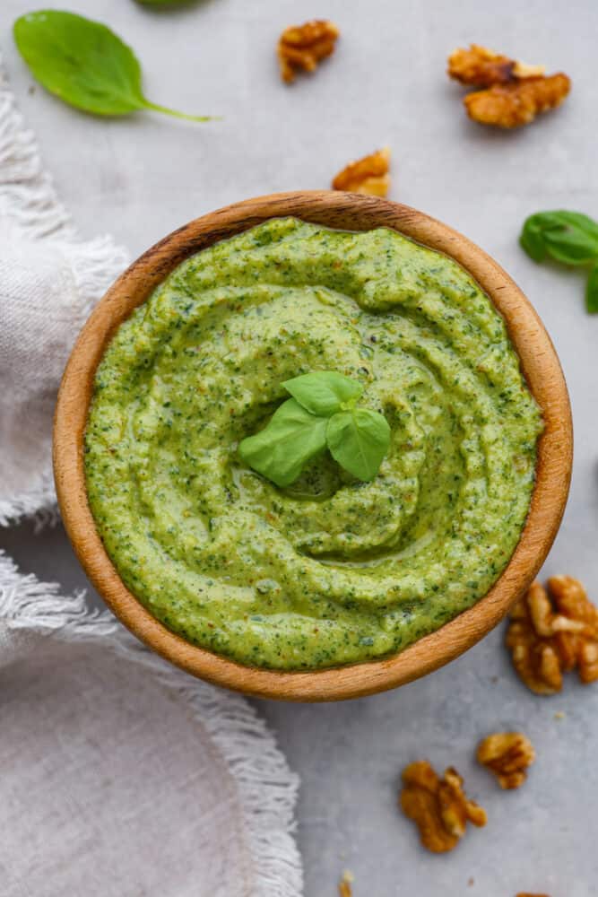 Move over, traditional basil pesto, there's a new nut in town! Walnut pesto is the perfect combination of earthy, nutty goodness with just the right amount of zing. You won't want it any other way. Spread it on chicken, toss it with pasta, or even eat it by the spoonful- no judgement here! Top-down view of walnut pesto in a wooden bowl.