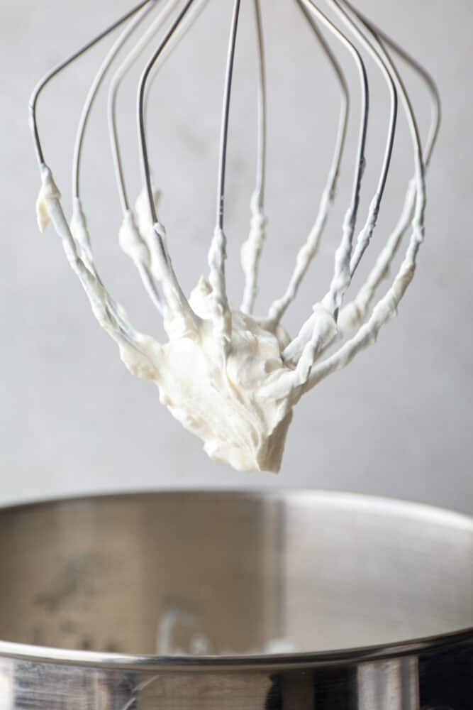 Stop running to the store for Cool Whip, this homemade Whipped Cream is so much better! It's real fresh cream without added preservatives or flavors, and it makes the perfect topping for your cakes, cobblers, and sundaes. Whipped cream on a whisk.