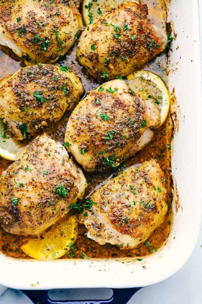 Baked Chicken Thighs are tender and juicy and baked in an AMAZING glaze mixture of Italian seasoning, Dijon mustard, sweet honey, and garlic cloves. This is a MUST make family meal! Baked chicken thighs in a white pan.