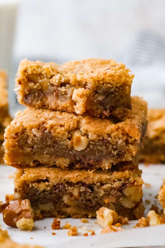 These chewy brown butter blondies are enhanced with the rich flavor of browned butter and loaded with (optional) nuts and candy pieces. Don't worry if you've never browned butter before, it's easy and I'll walk you through the steps below! A close up on brown butter blondies stacked on top of each other.