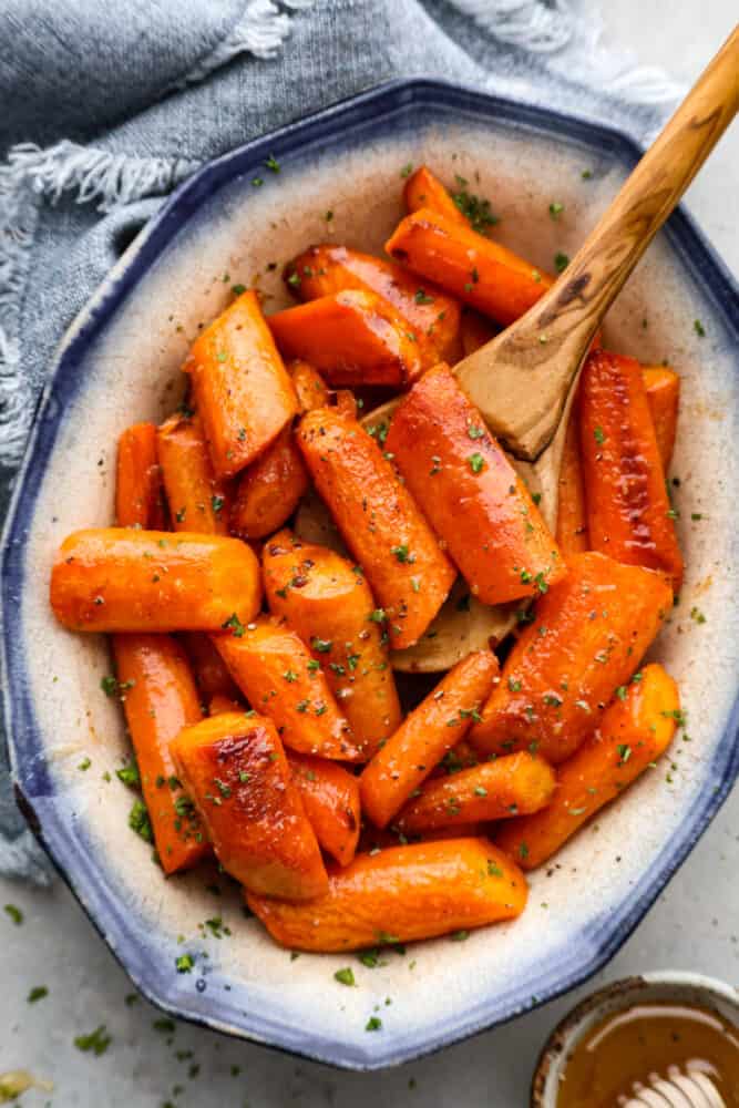 Roasted brown butter honey garlic carrots make an excellent side dish. Roasted to tender perfection in the most incredible sauce these will instantly become a new favorite! Top-down view of brown butter carrots in a blue and white bowl.