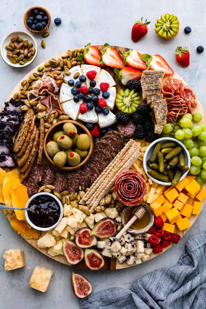 Charcuterie boards are the ultimate party trick that never fail to impress! These beautiful displays of meats, cheeses, fruits, and nuts are not only eye-catching but also incredibly delicious. Don't be intimidated by how Pinterest-worthy they look, because assembling one is a lot easier than you think. Here are all the ins and outs on how to make a charcuterie board at home! Hero image of a charcuterie board topped with various cheese, fruit, meats, nuts, and crackers.