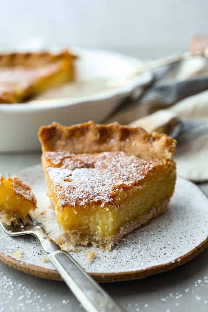 This classic Southern dessert is a delicious combination of sweet, tangy, and buttery flavors all wrapped up in a flaky crust. Its custard-like filling has a smooth and creamy texture that will have you hooked. And the best part? Chess pie is super easy to make and only takes 10 minutes of prep! Front view of a slice of pie with a bite taken out of it.