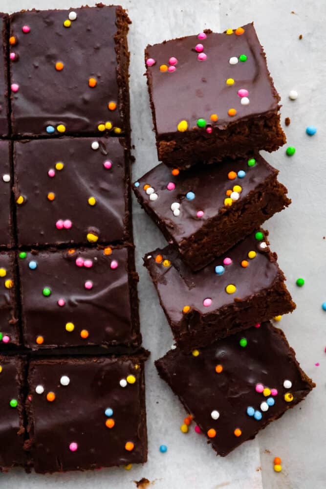 Brace yourself for a cosmic trip down memory lane! Homemade cosmic brownies are here to take you back to your childhood, one fudgy bite at a time. Because let's be real, there's no better way to relive the good old days than with a sprinkle-studded treat that's out of this world! Top-down view of Cosmic Brownies that have been cut into squares.