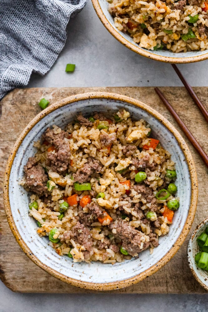 This easy Beef Fried Rice is ready in under 30 minutes and so delicious! It's a great way to reinvent leftover rice into a filling and satisfying meal that the whole family will love. With just a few simple ingredients, you'll find yourself making this recipe all the time! Beef fried rice in a bowl with chop sticks next to it.