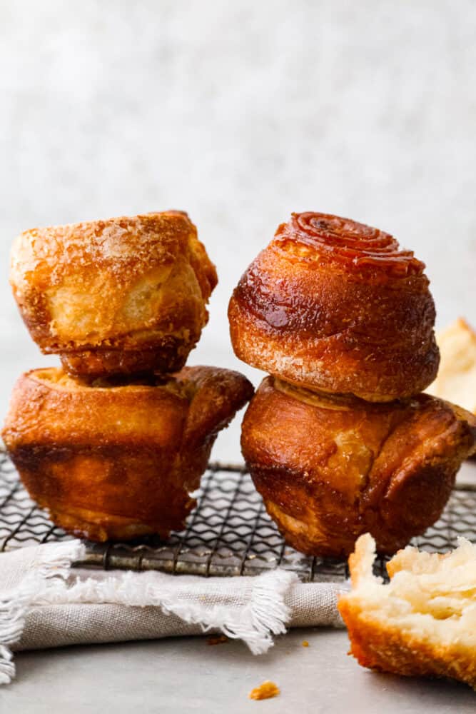 Imagine a sticky bun and a croissant put together and you have a delicious Kouign Amman! It's a laminated sweet dough that you will absolutely fall in love with. Don't be intimidated by this recipe, I break it down step by step into simple to follow instructions that will turn out great every single time! A side view of kouign amman stacked on top of each other.