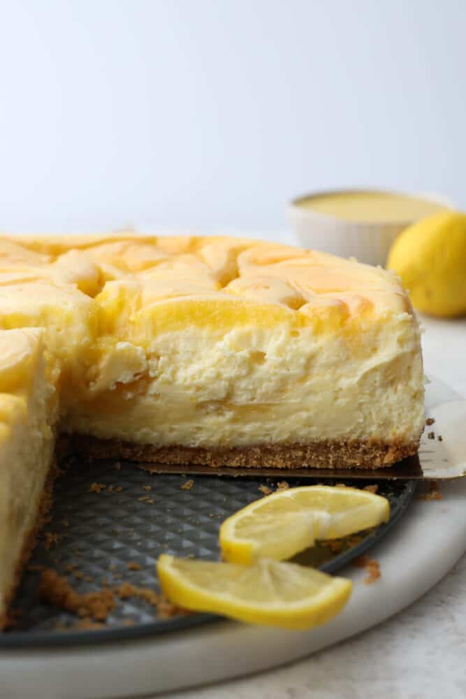 Trust me, you need this dreamy lemon cheesecake in your life. The lemon curd adds the perfect tangy kick to the creamy cheesecake filling, making every bite a smooth, heavenly experience. One slice just won't cut it, you'll want to indulge in the whole cake! Cheesecake with a slice cut out of it.