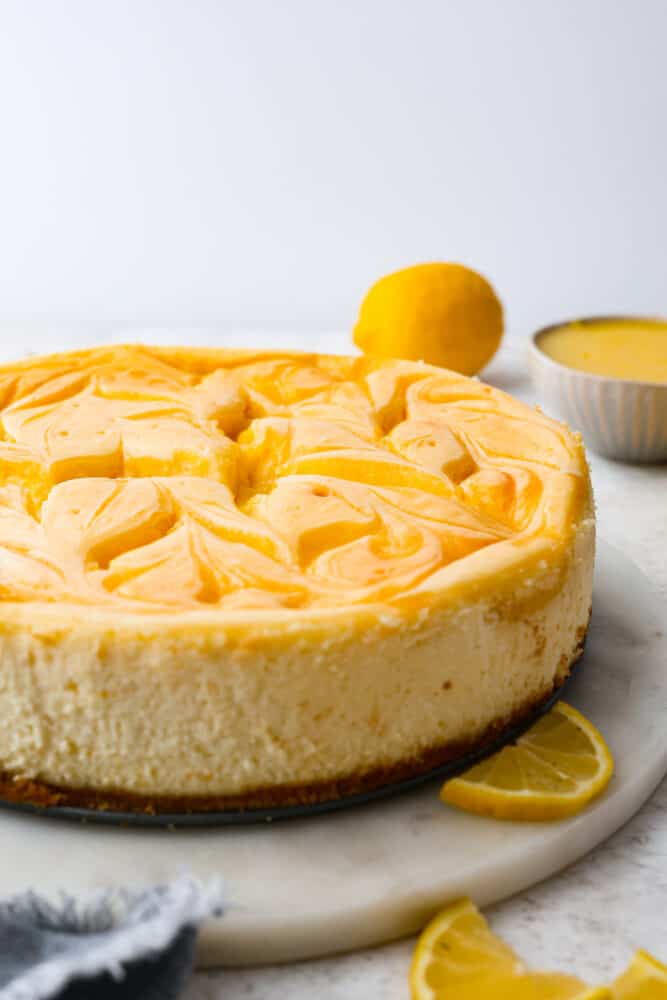 Trust me, you need this dreamy lemon cheesecake in your life. The lemon curd adds the perfect tangy kick to the creamy cheesecake filling, making every bite a smooth, heavenly experience. One slice just won't cut it, you'll want to indulge in the whole cake! A whole cheesecake topped with swirls of lemon curd.