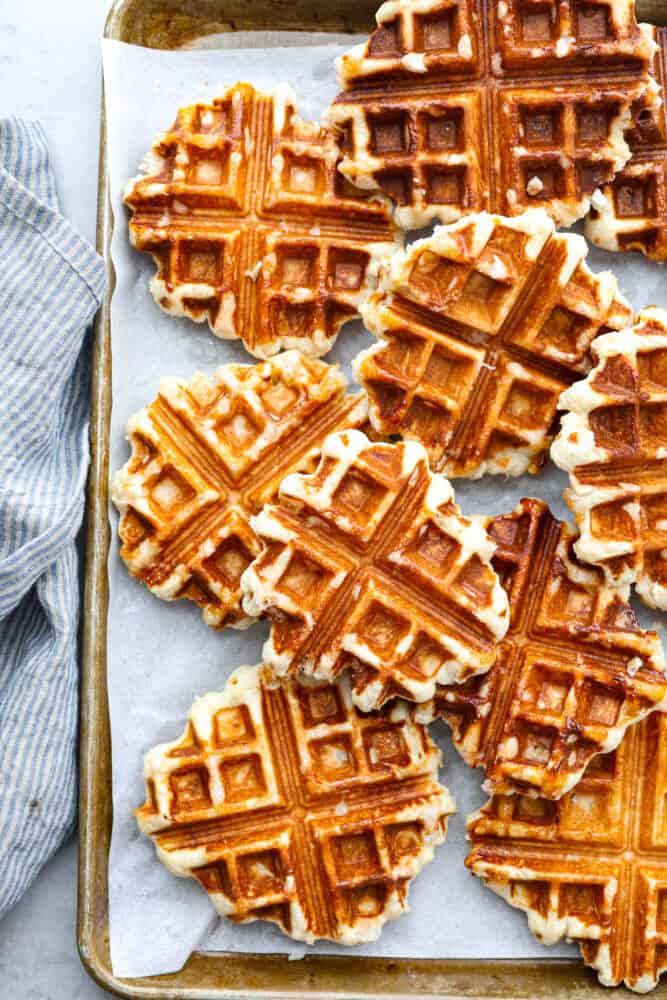 You've never had a waffle like a Liege Waffle! These waffles are similar to a Belgian waffle but made sweeter by pearl sugar. They are perfectly crispy on the outside and warm and soft on the inside. Topped with fresh berries and whipped cream, you won't find a better brunch companion! Liege waffles on a sheet pan lined with parchment.