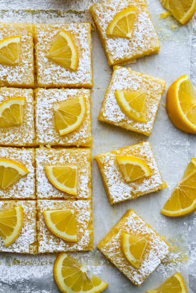 There’s nothing better than a buttery shortbread crust topped with a juicy lemon filling and a sprinkling of powder sugar. This classic recipe for lemon bars is the only one you’ll ever need! It’s happiness in bite-sized pieces. Top-down view of lemon bars cut into squares.