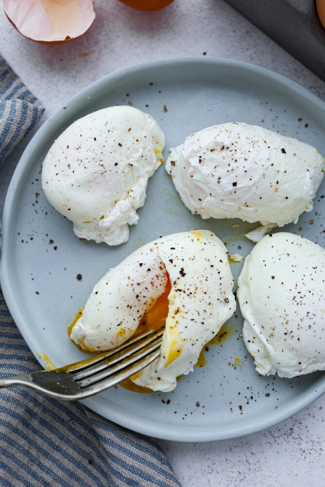 Soft egg whites and warm runny yolks are reason enough for every home chef to know how to poach an egg! It's not as hard as it sounds, and these eggs are so next level you won't believe what you've been missing out on all these years! Poached eggs on a plate with a fork cutting into one of them