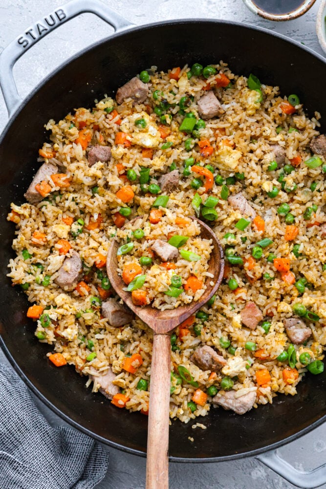 You guys know how I feel about fried rice, itโs my go-to for leftover rice and whatever meatโs in the fridge. Pork Fried Rice is savory and satisfying. With tender pork, fluffy eggs, and veggies all in one pan, itโs the ultimate weeknight win. A pot of pork fried rice with a wooden spoon in it.
