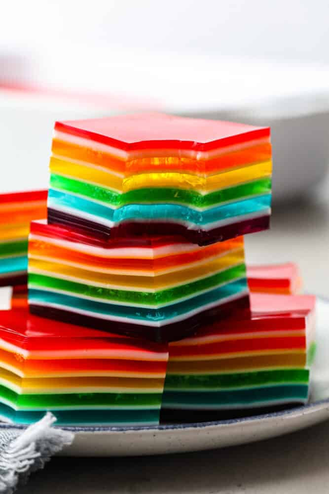 Taste the Rainbow! Whether it's a birthday party, St. Patrick's Day, or just a fun summer BBQ, rainbow Jello is always a crowd-pleaser. Plus, who doesn't love a dessert that's literally bursting with color? Jello squares stacked on top of each other, one has a bite taken out of it.