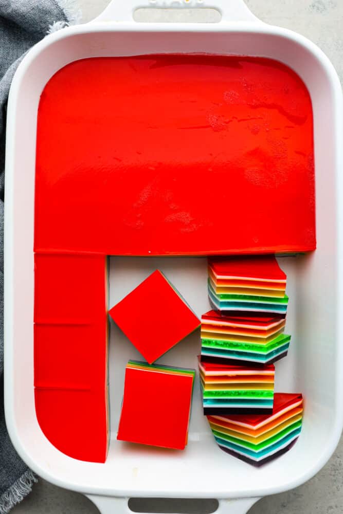 Taste the Rainbow! Whether it's a birthday party, St. Patrick's Day, or just a fun summer BBQ, rainbow Jello is always a crowd-pleaser. Plus, who doesn't love a dessert that's literally bursting with color? Top-down view of a pan of rainbow jello being cut into squares.