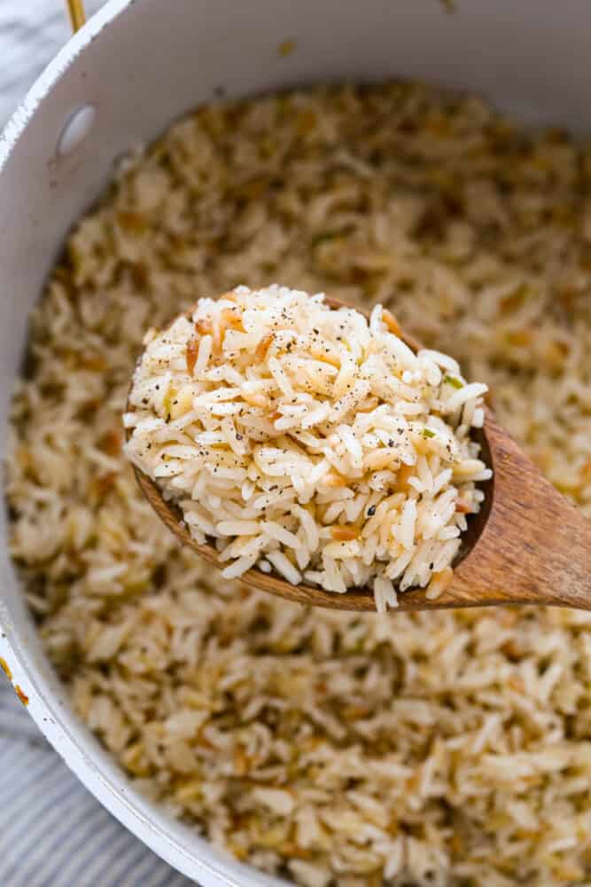 The combination of tender rice, toasty orzo, savory chicken broth, and aromatic green onions creates a mouth-watering medley that will have you coming back for seconds (and maybe even thirds!). Trust me, this rice pilaf will become a staple side dish in your kitchen once you give it a try. It's perfect for pairing with all of your favorite meals! Closeup of a spoonful of seasoned rice and orzo.
