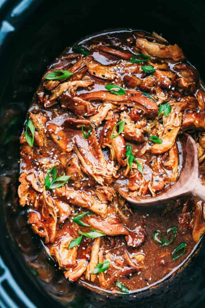 Slow Cooker Honey Garlic Chicken is always a hit at my house! It's chicken thighs cooked in a honey garlic sauce that is infused with soy and hoisin sauce with fresh garlic and ginger covering the boneless chicken thighs for one amazing family dinner. Throw it all together and let the slow cooker do all the work! Slow cooker honey garlic chicken in the crock pot with a wooden spoon.