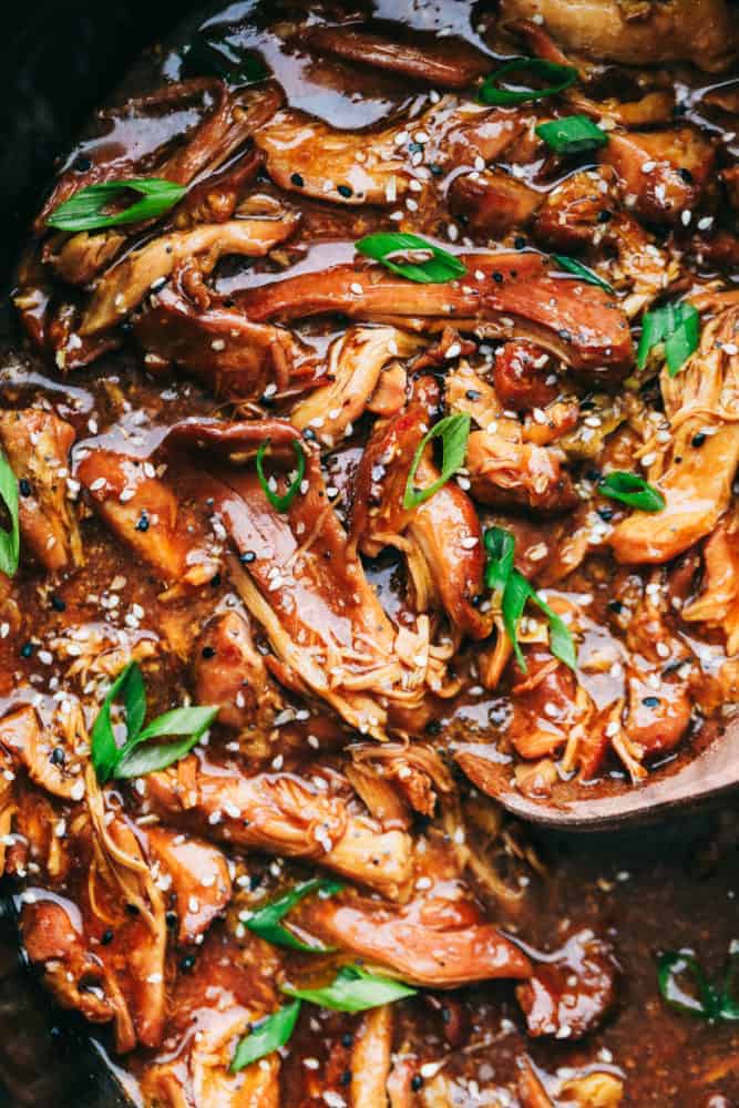 Slow Cooker Honey Garlic Chicken is always a hit at my house! It's chicken thighs cooked in a honey garlic sauce that is infused with soy and hoisin sauce with fresh garlic and ginger covering the boneless chicken thighs for one amazing family dinner. Throw it all together and let the slow cooker do all the work! A close up on the chicken in the crock pot.