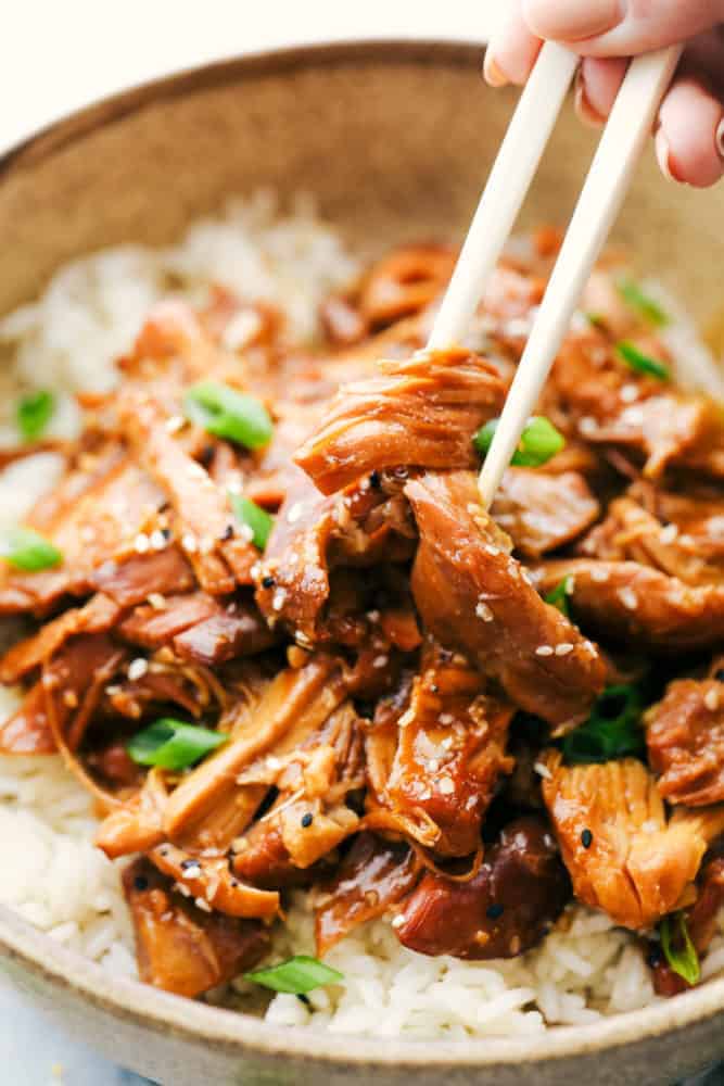 Slow Cooker Honey Garlic Chicken is always a hit at my house! It's chicken thighs cooked in a honey garlic sauce that is infused with soy and hoisin sauce with fresh garlic and ginger covering the boneless chicken thighs for one amazing family dinner. Throw it all together and let the slow cooker do all the work! Slow cooker honey garlic chicken in. a bowl.