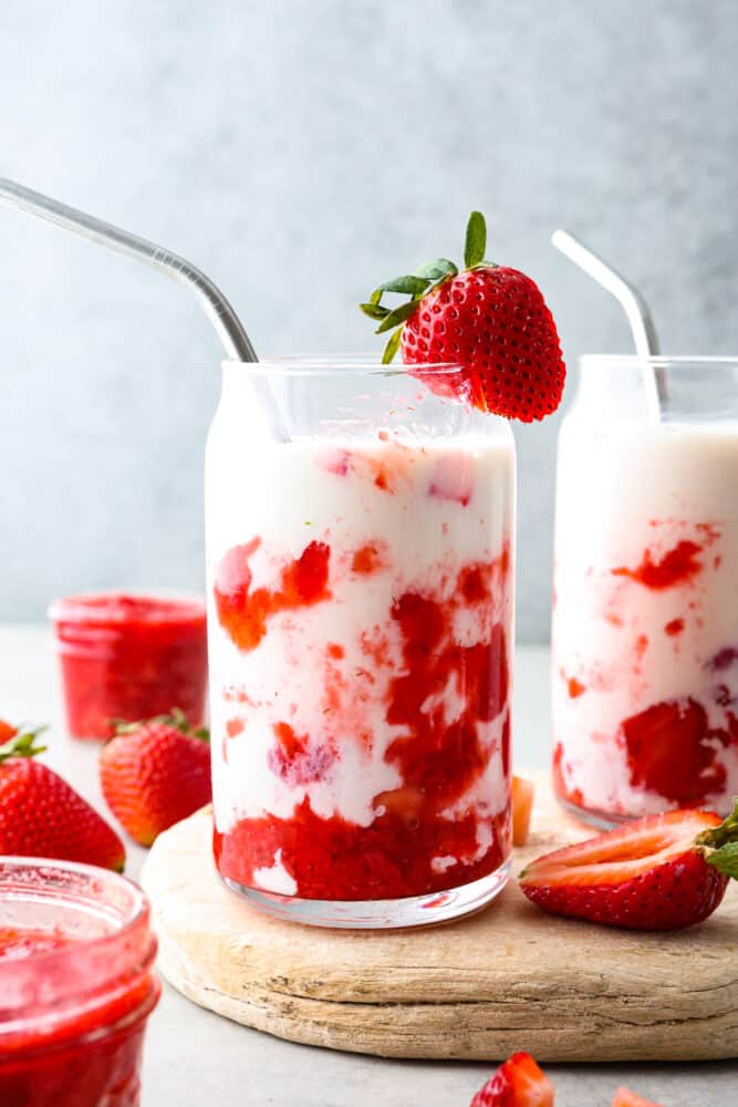 Homemade Korean strawberry milk is a sweet and fruity treat that is sure to satisfy your taste buds. The blend of fresh strawberries and creamy milk creates a perfectly balanced flavor that is both indulgent and refreshing. Sipping on a glass of this cute and tasty beverage brings the café culture of Seoul straight to your kitchen! 2 glasses of strawberry milk served on a wooden board.