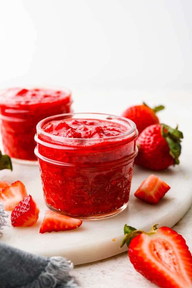 This quick and easy recipe for Homemade Strawberry Sauce is a must-have! This is a great way to use up fresh summer strawberries or to keep the ones you have in the fridge from going bad. I include plenty of tips for making your sauce thinner or thicker and glossier, too! Strawberry sauce in a cute little mason jar.