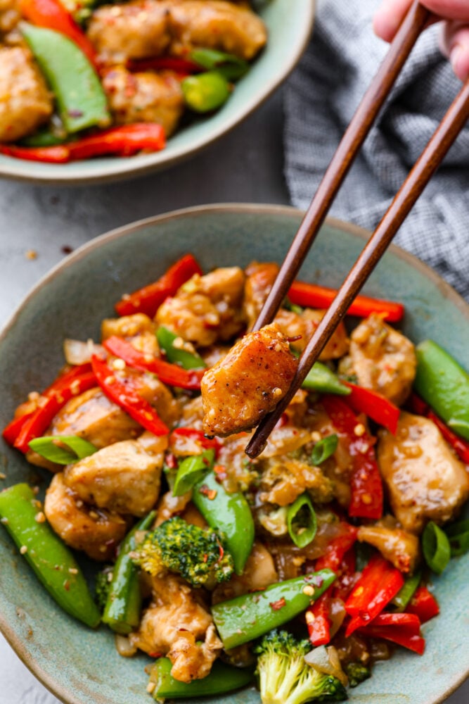 Szechuan chicken is all about bold flavors, with the perfect balance of heat, sweetness, and tanginess. And the best part? It's way better than the takeout version! Let's fire up those taste buds and get cooking! Picking up a piece of chicken with chopsticks.
