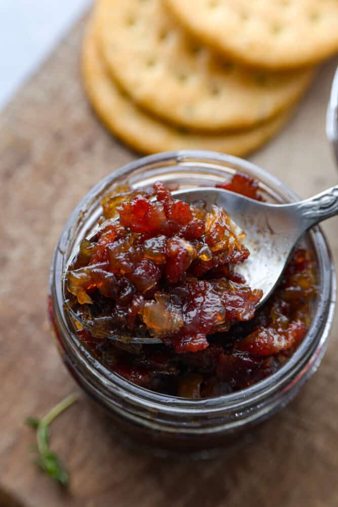 I know it may sound like an unusual combination, but trust me when I say bacon jam is a game-changer. This sweet and savory spread, made with crispy bacon, caramelized onions, and a touch of maple syrup, can elevate any dish from ordinary to extraordinary. It has a sweet and savory flavor that goes well with so many different foods, from toast and crackers to burgers and sandwiches. Closeup of bacon jam on a metal spoon.