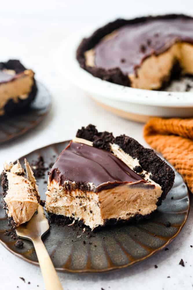 A fluffy, whipped peanut butter filling on top of an Oreo crust, all topped with chocolate ganache- what could be better than that? This chocolate peanut butter pie is the perfect dessert for anyone wanting something smooth, rich and indulgent! A slice of peanut butter pie with a bite taken out of it.