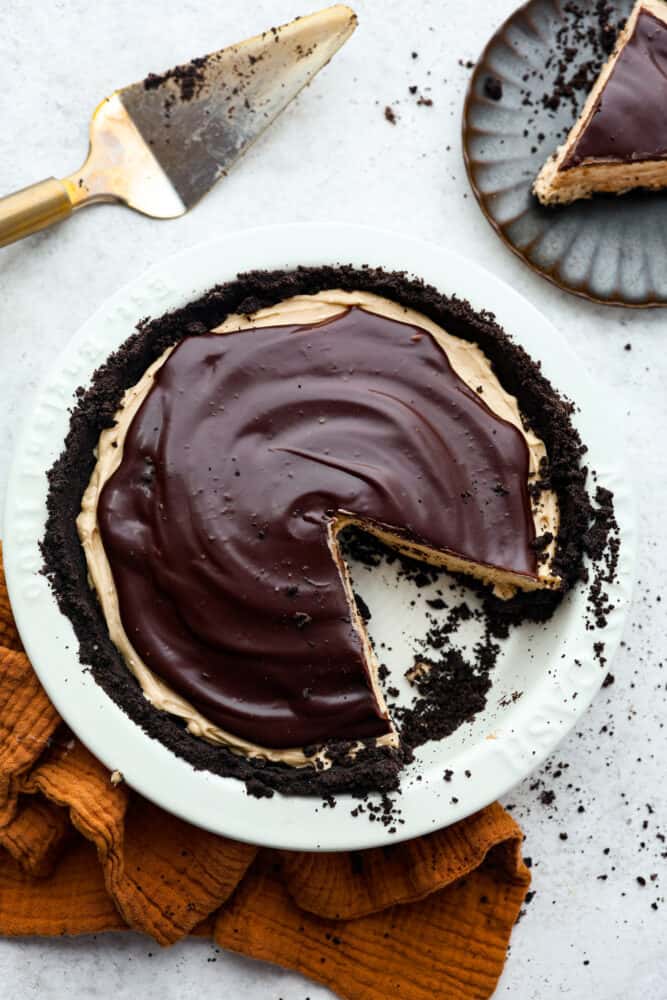 A fluffy, whipped peanut butter filling on top of an Oreo crust, all topped with chocolate ganache- what could be better than that? This chocolate peanut butter pie is the perfect dessert for anyone wanting something smooth, rich and indulgent! Top-down view of chocolate peanut butter pie with a slice cut out of it.
