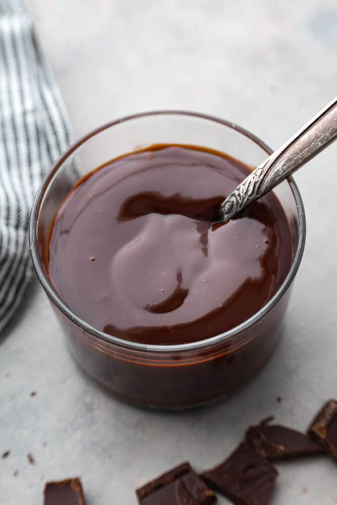 Everyone needs a great chocolate ganache recipe in their cookbook! This recipe is a classic and the best ganache recipe I've ever tried. It's perfectly shiny with rich chocolate flavor, and takes 5 minutes to whip up! An overhead view of chocolate ganache in a glass container.