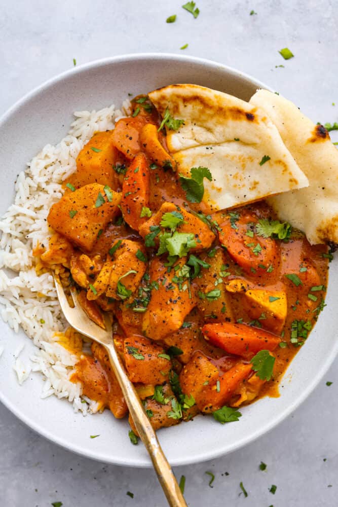 Coconut curry chicken is a mouthwatering dish that combines tender chicken, hearty vegetables, and a blend of aromatic spices, all simmered in a luscious coconut milk sauce. Serve it up with naan and basmati rice for a meal your family won’t be able to get enough of! Coconut curry served over white rice with naan.