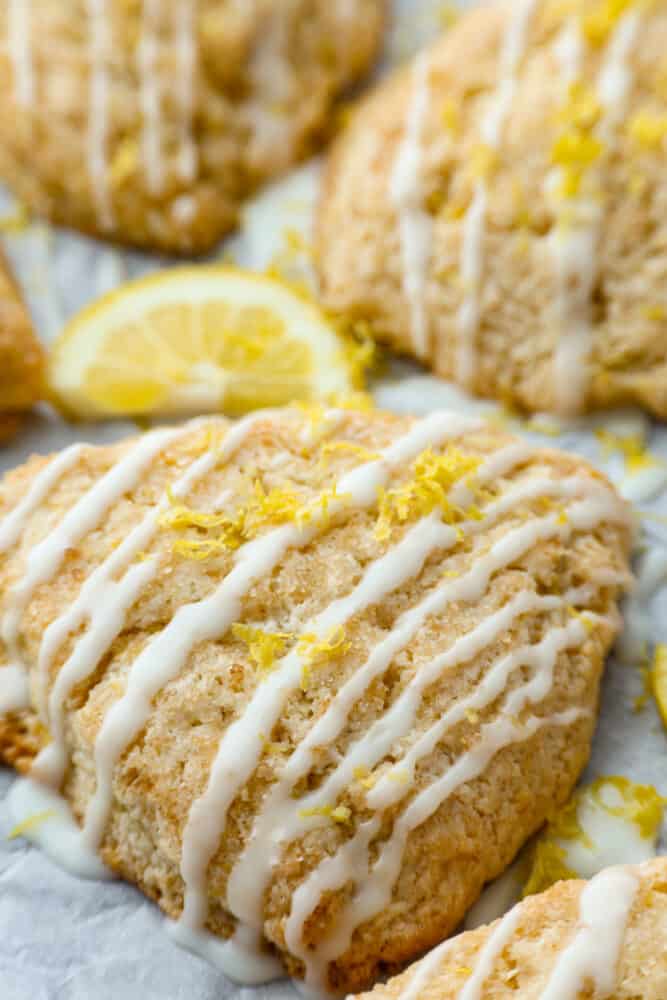 These homemade lemon scones are the perfect balance of tangy and sweet, with a crumbly texture that'll melt in your mouth. And let's not forget about the delicious sweet lemon icing, which is the cherry on top to make them simply irresistible. Having one of these for breakfast is the perfect way to start your day! Closeup of a lemon scone.