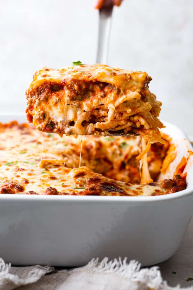 This Million Dollar Spaghetti casserole has the perfect name- it really tastes like a million bucks! It's the perfect combination of lasagna and spaghetti, how can it get better than that? Million dollar spaghetti slice being lifted out of the casserole dish.