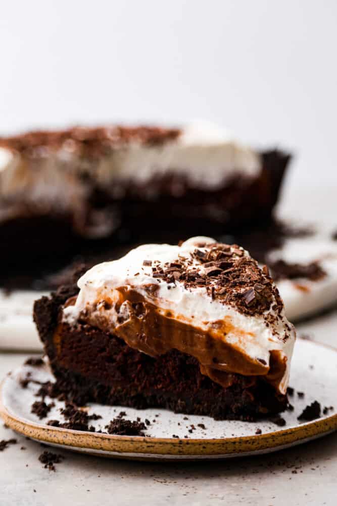 Chocolate lovers, this Mississippi Mud Pie is for you! A silky chocolate filling topped with whipped cream and chocolate shavings, all eaten on an Oreo crust. It doesn't get much more delicious than that! A slice of Mississippi mud pie on a plate.