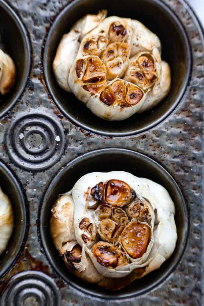 If you want to infuse your favorite recipes with savory, nutty flavor, roasted garlic is the way to go! You can easily make some at home in a muffin tin with a drizzle of olive oil on top to enhance the overall flavor! The end result is caramelized, garlic heaven. Closeup of roasted garlic.