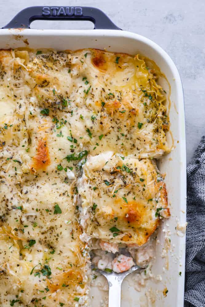 If youโre a seafood lover, you'll be obsessed with this Seafood Lasagna. Iโm talking crab, scallops, and shrimp in creamy, cheesy layers, baked to bubbly perfection. Itโs my go-to dinner when Iโm cooking for seafood fans! Top view of a spatula in the pan of seafood lasagna ready to lift out a slice.