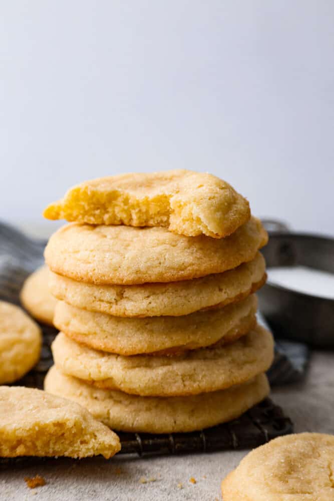 These soft sugar cookies are perfectly chewy on the inside with sweet golden edges on the outside! The drop-style method makes these the easiest sugar cookies you will ever make, and everyone will fall in love with the chewy texture. Overhead view of soft sugar cookies stacked on a cooling rack.