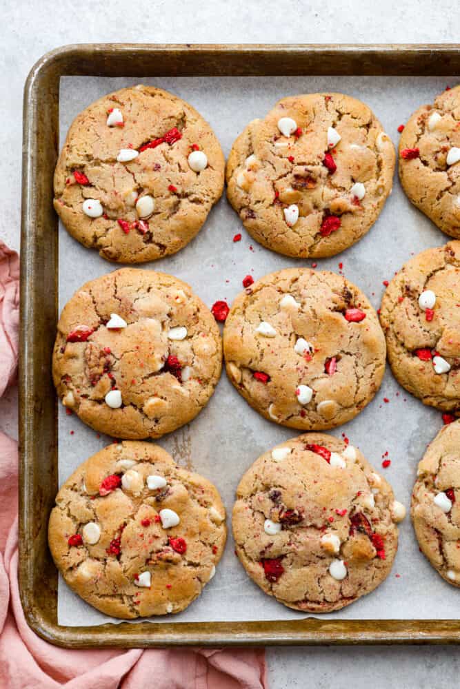Meet your new favorite cookie recipe: soft and sweet strawberry cookies filled with a gooey cheesecake center. These golden-brown morsels of goodness will be devoured as soon as theyโre out of the oven! Top-down view of baked strawberry cheesecake cookies.