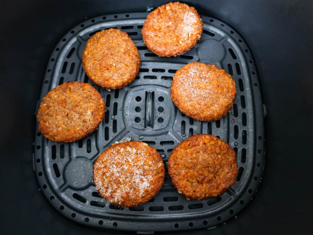 For a quick and delicious breakfast, try making frozen sausage patties in the air fryer! In less than 10 minutes they turn tender and juicy, perfect for adding to your favorite English muffins! Frozen patties in an air fryer basket.