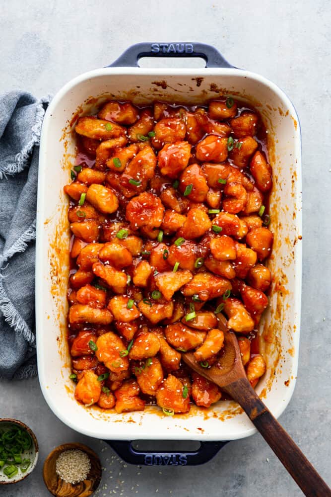 Baked Sweet and Sour Chicken is 1000x better than any takeout! It's crispy on the outside, juicy on the inside and exploding with flavor. There is a reason why this is our favorite recipe on the blog! Top-down view of baked chicken in a white dish.