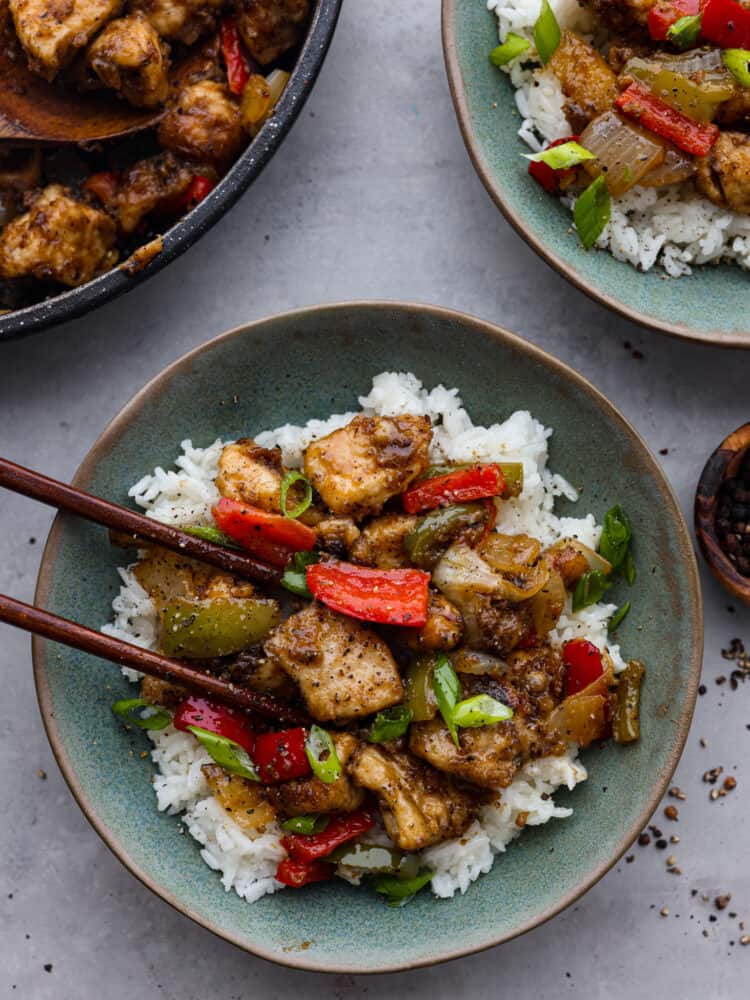 If you want to add a burst of flavor to weeknight dinners, this Chinese-inspired black pepper chicken is the perfect recipe to try! With its amazing homemade sauce, each bite is packed with savory, peppery, and slightly tangy flavors that will leave your mouth watering. Chicken served over rice in a teal bowl.
