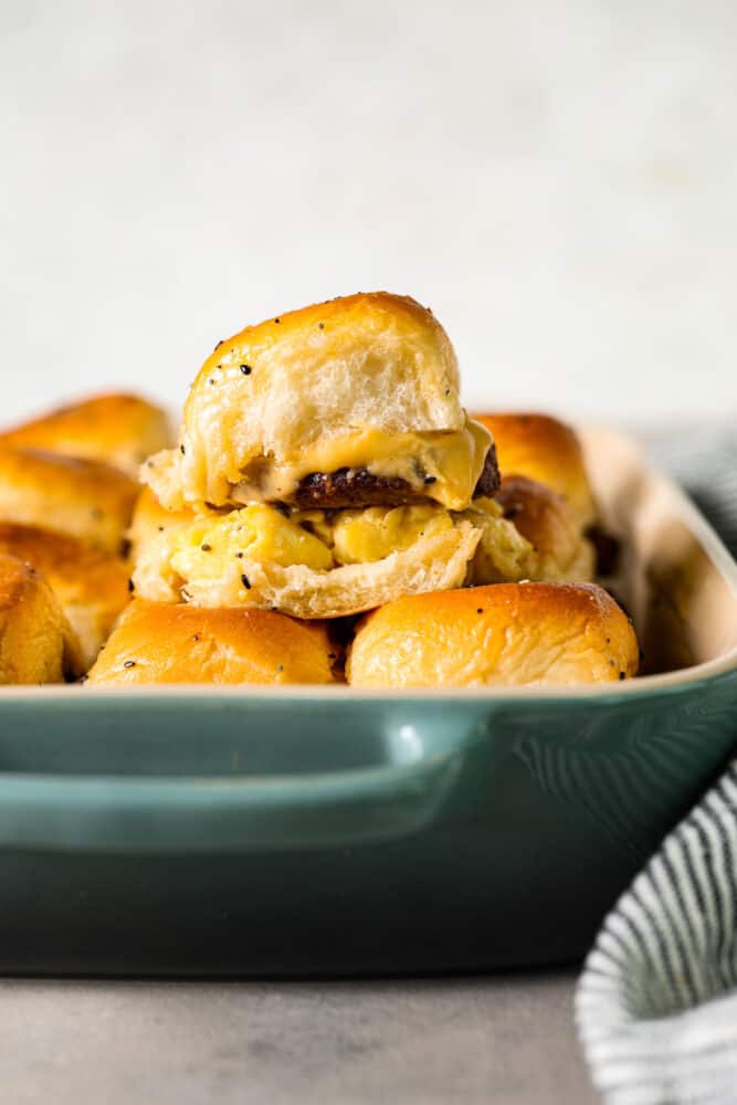 Hawaiian rolls filled with juicy sausage patties, scrambled eggs, and melty cheese, slathered in everything bagel butter. These breakfast sliders are so simple, so delicious, and perfect for feeding a crowd. Sliders stacked on top of each other.