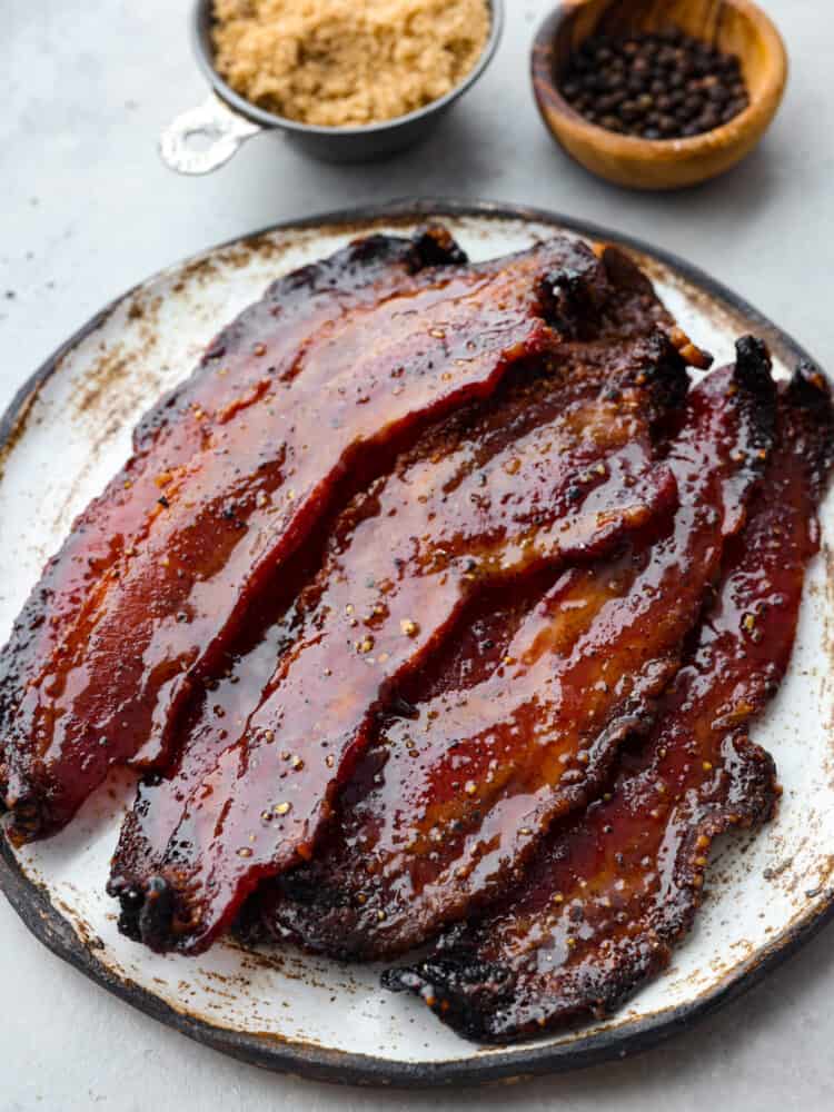Once you try candied bacon, you wonโt want it any other way. Thick-cut slices of bacon in a caramelized brown sugar coating, topped off with a pinch of black pepper and cayenne - what could be better? Itโs a flavor combination you wonโt be able to stop thinking about. Top down view of candied bacon served on a stoneware plate.