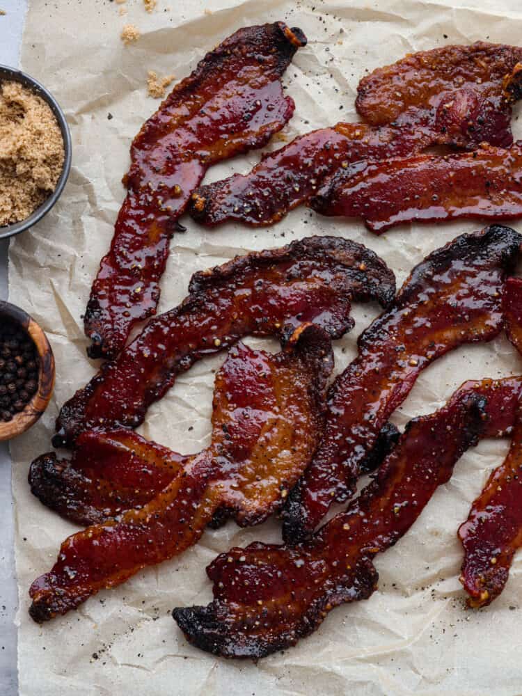 Once you try candied bacon, you wonโt want it any other way. Thick-cut slices of bacon in a caramelized brown sugar coating, topped off with a pinch of black pepper and cayenne - what could be better? Itโs a flavor combination you wonโt be able to stop thinking about. Cooked bacon on parchment paper.