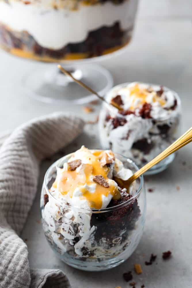 A classic English dessert that is every chocolate loverโs dream! This chocolate trifle is made with layers of devilโs food cake, caramel sauce, whipped cream, and toffee bits that will have you savoring each and every bite. Chocolate cake, whipped cream, and caramel served in small glasses.