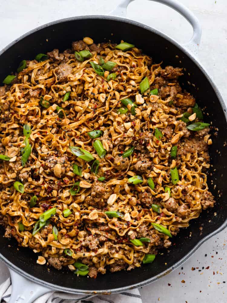 Dan Dan Noodles is a classic Chinese dish made with tender egg noodles and flavorful minced pork tossed in a savory, slightly spicy sauce. It's the perfect comfort food and will have everyone in your family wanting seconds. Top-down view of dan dan noodles in a skillet.