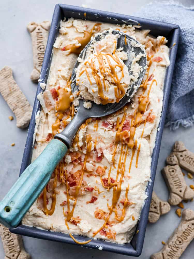 Keep your pup cool and happy this summer with a scoop of dog ice cream! This frosty treat is made with peanut butter, banana, and plain yogurt, topped with crispy bacon bits. Your fur baby won't be able to get enough. Dog ice cream in a bread pan with a scoop taken out of it.